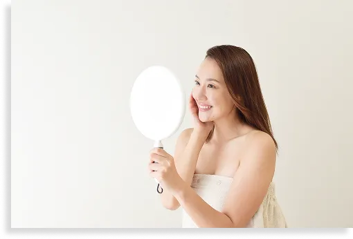 鏡を見て肌の変化に微笑む女性